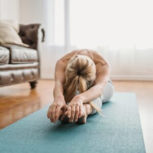 A woman performs a yoga stretch on a mat in a cozy living room, embracing wellness and relaxation.